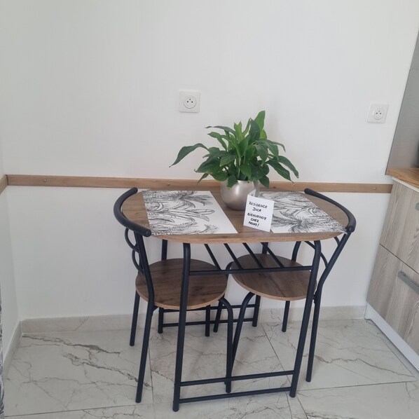 A small dining table with a potted plant, two chairs, and a sign reading "RESIDENCE BIENVENUE NOUS". - Studio 30 meters, close to marina (Port-Saint-Louis-du-Rhône)