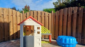 Une cabane de jeu pour enfants avec un toit rouge, une petite porte et une fenêtre.