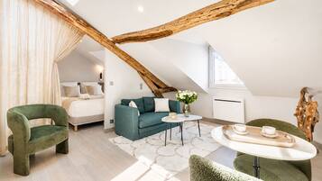 Un dormitorio estilo loft moderno con techo inclinado, un sofá, una mesa de centro y un sillón verde.