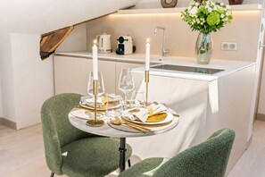 A dining area with a table set for two, featuring a white tablecloth, two candles, and glassware. - 1537 Bourg Tibourg (Paris)