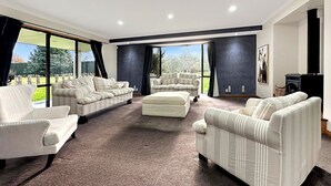 A spacious living room with a large window, a fireplace, and a view of the outdoors. - Spacious Escape on Busch Lane (Christchurch)