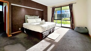 A bedroom with a bed, a large window, and a view of the outdoors. - Spacious Escape on Busch Lane (Christchurch)