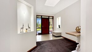 A hallway with a dark carpet, a red door, and a small white bench. - Spacious Escape on Busch Lane (Christchurch)