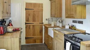 Une cuisine avec des meubles de rangement en bois, une cuisinière et une porte dotée d’une poignée noire.