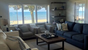 Un salón con vista a la playa, un ventilador de techo y una estantería.