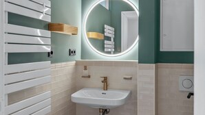 Een badkamer met een witte wastafel, een ronde spiegel en een handdoekhouder.