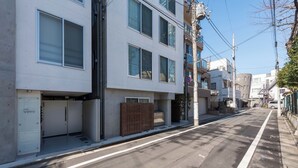 A modern urban street with a white building featuring multiple windows and a gated entrance. - Fare Metallo Hote 1-Doube bedroom 202 , Nakano City, Near Shinjyuku (Nakano City)