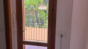 A door with a view of a balcony, a power outlet, and a wall-mounted light switch.