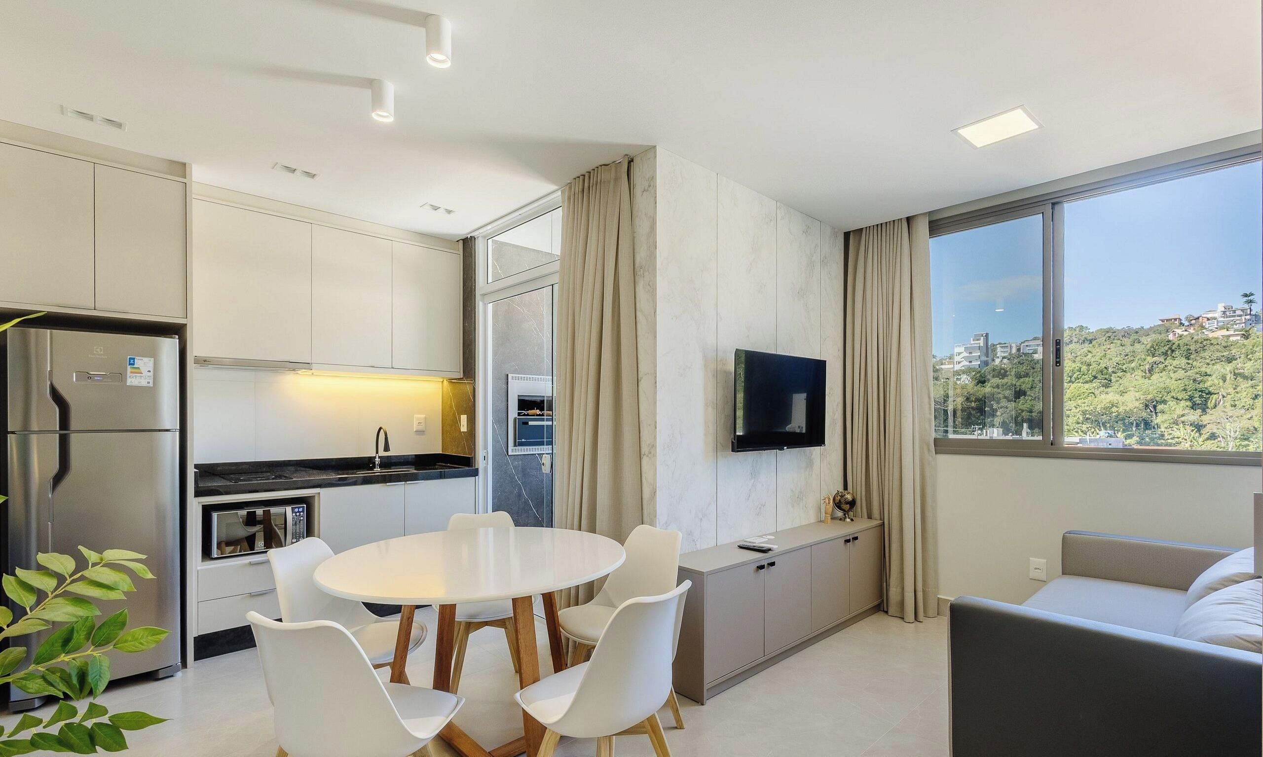 Una cocina moderna con comedor, televisor de pantalla plana y un amplio ventanal con vista a la ciudad.