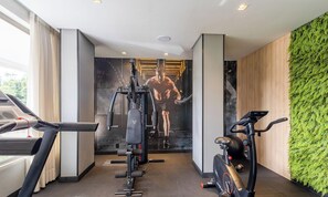 A gym with exercise equipment, a treadmill, and a wall with a fitness illustration. - Your Exclusive Stay With Pool and Jacuzzi Just 500 Meters From the Beach - ELF (Bombinhas)