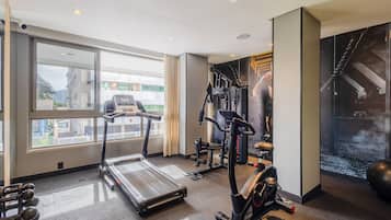 Un gimnasio con cintas de correr, elípticas y pesas libres.