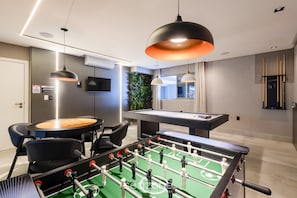 A modern room with a foosball table, a pool table, and a billiards table. There are two chairs and a sofa. - Your Exclusive Stay With Pool and Jacuzzi Just 500 Meters From the Beach - ELF (Bombinhas)