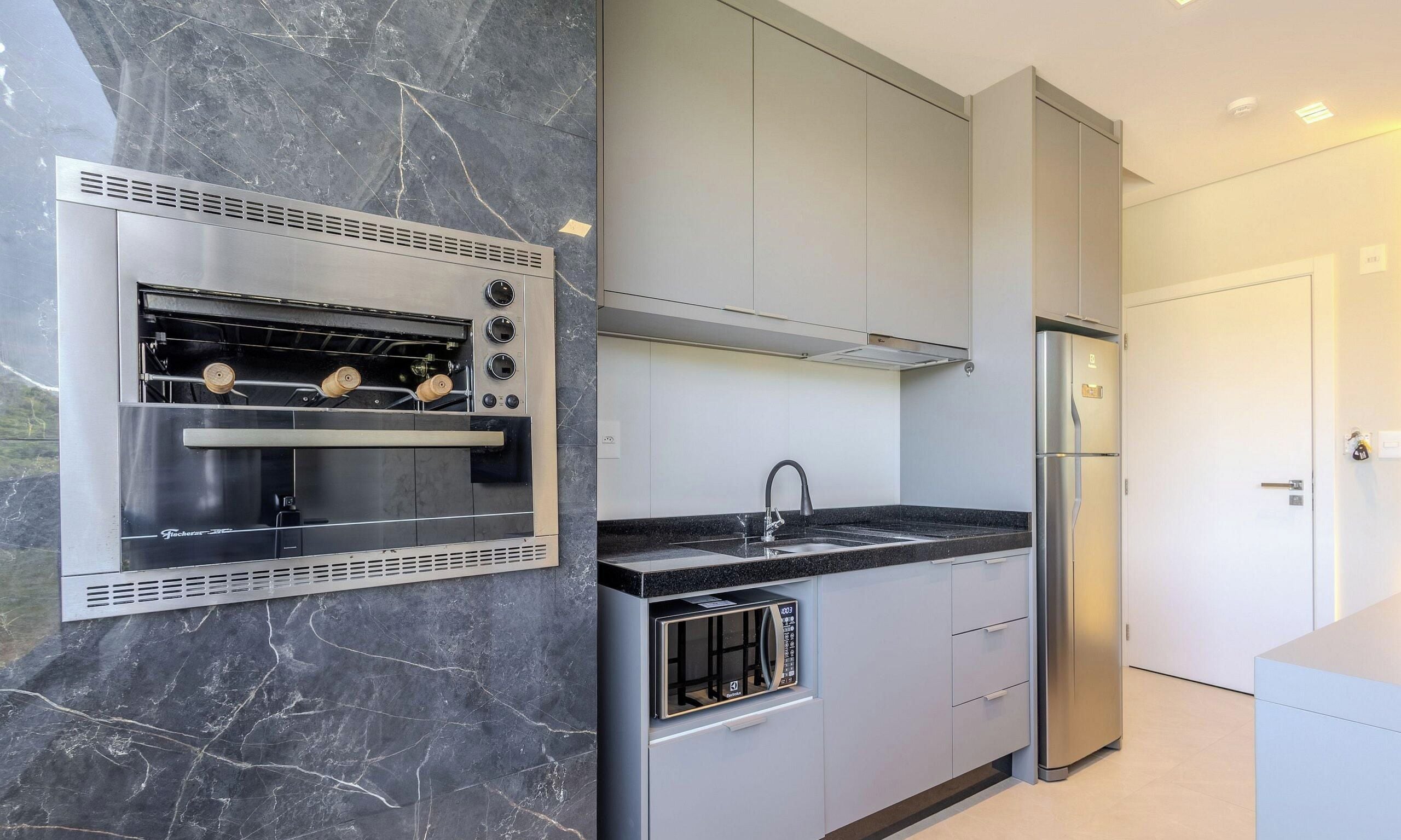 Una cocina moderna con electrodomésticos integrados, salpicadero de mármol y refrigerador de acero inoxidable.
