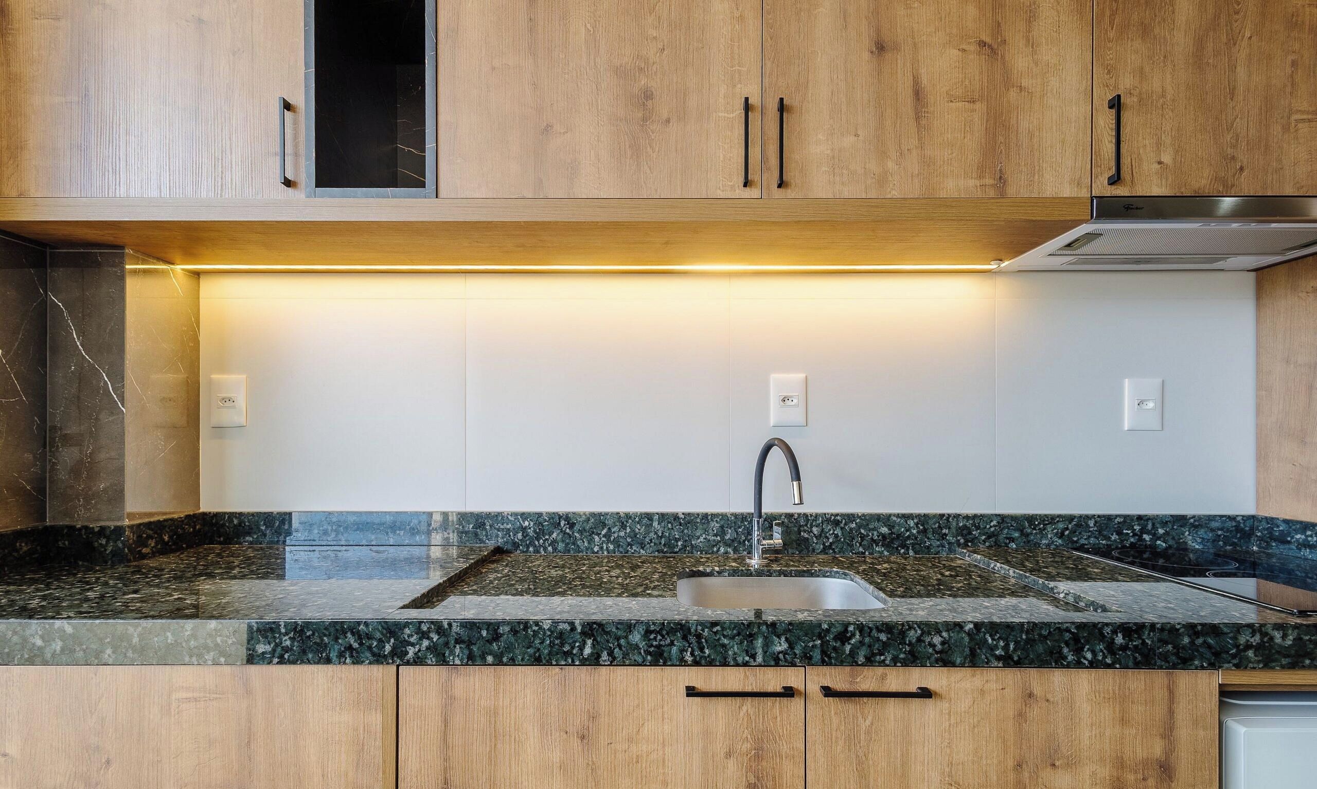 Una cocina con armarios de madera, un lavamanos de acero inoxidable y una campana extractora integrada.