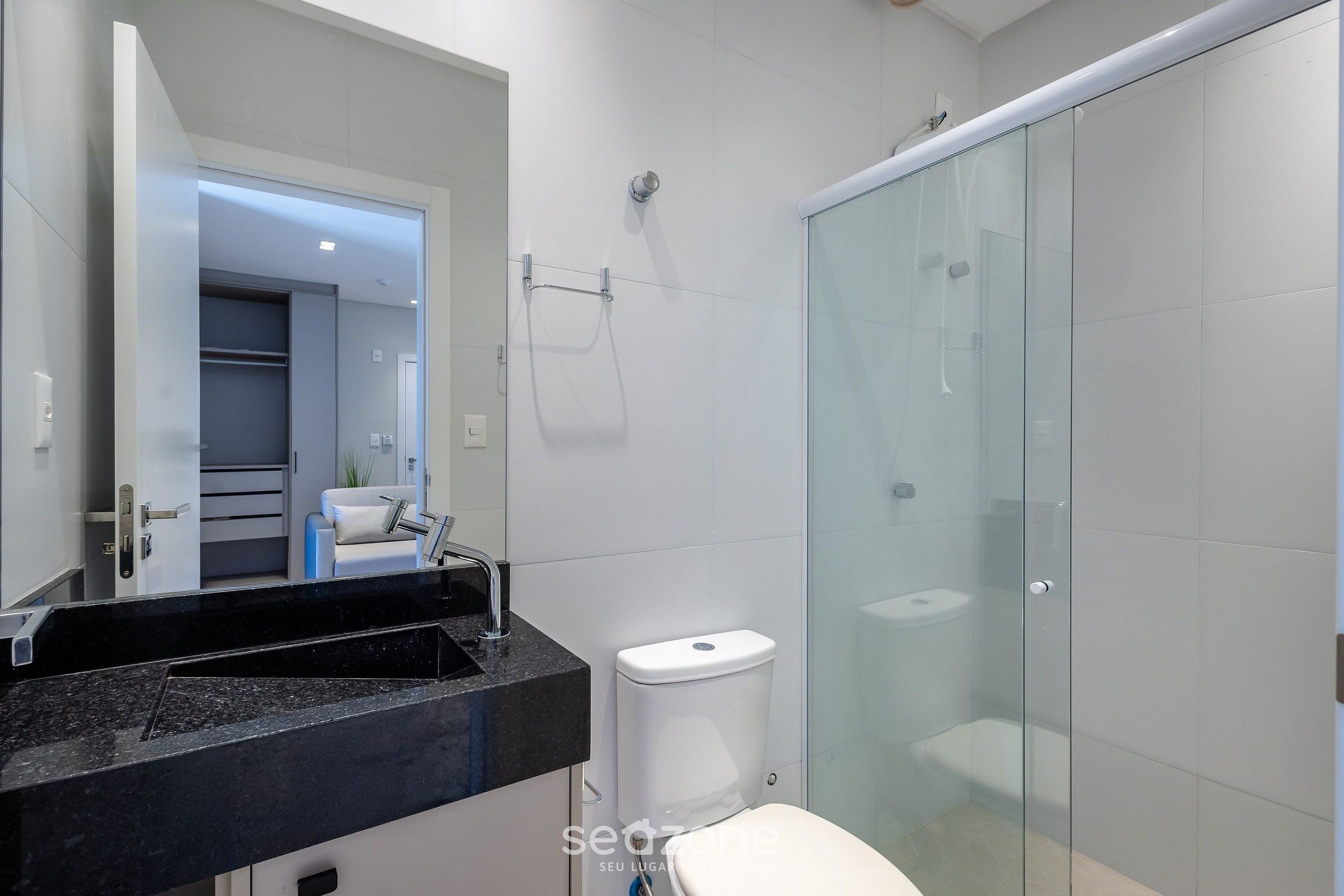A modern bathroom with a glass shower enclosure, a white toilet, and a black countertop sink.