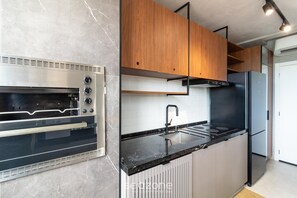 A modern kitchen with a built-in oven, a sink, and wooden cabinets.