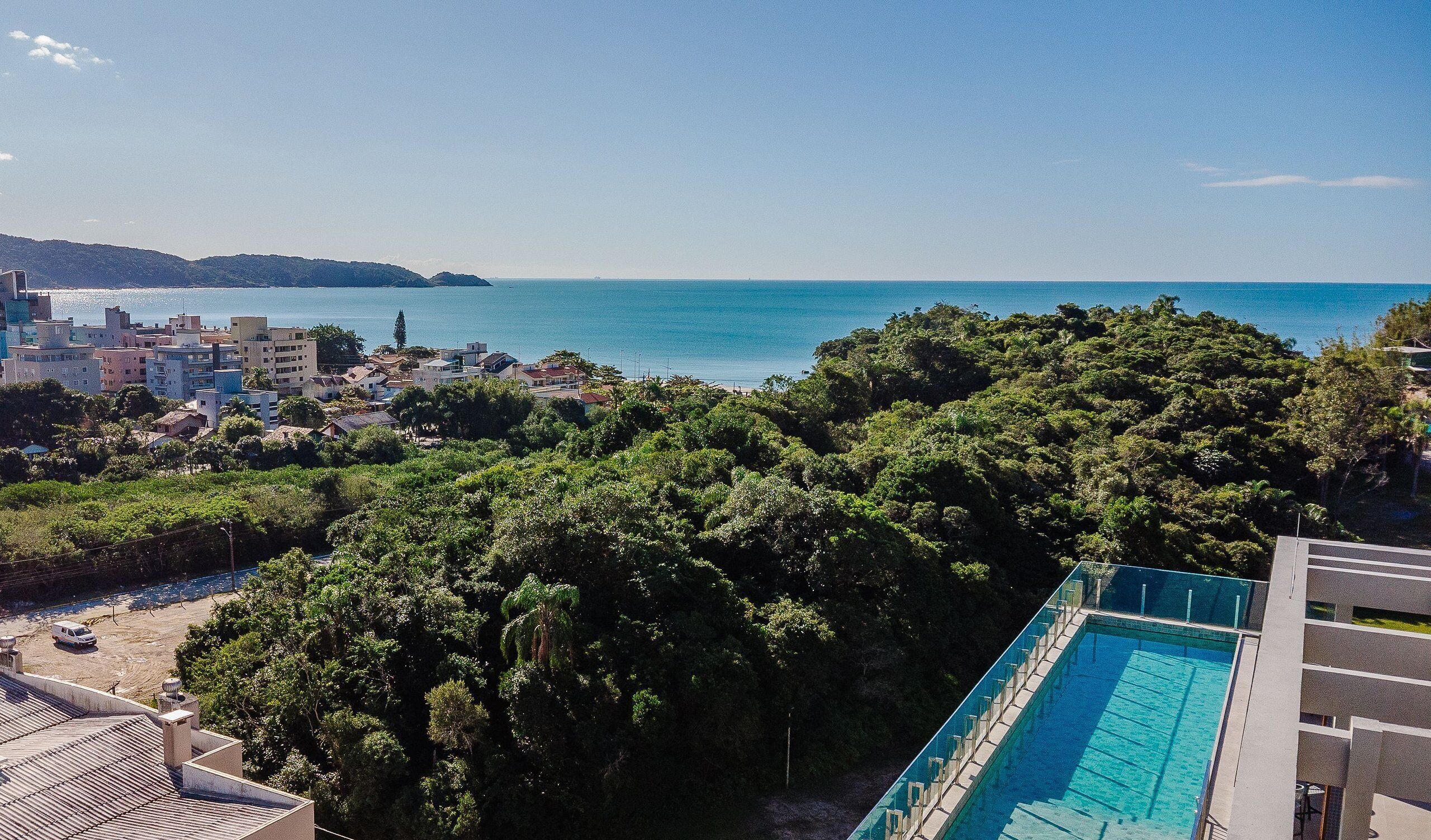 Zona residencial amb piscina, vegetació abundant i vista al mar.