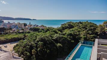 Zona residencial amb piscina, vegetació abundant i vista al mar.
