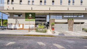 Un edificio moderno con fachada plana, un letrero que dice “Capital Empreendimentos” y una entrada con acceso restringido, que cuenta con una escalera que sube.
