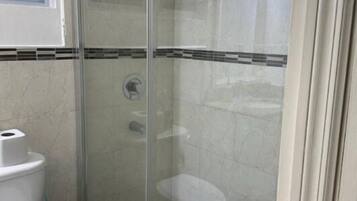 A bathroom with a glass-enclosed shower, a toilet, and a sink.