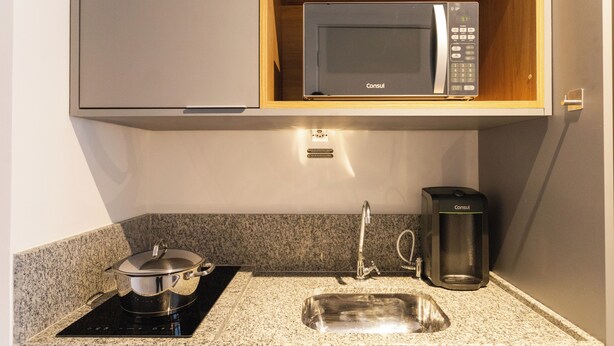 A compact kitchen with a built-in microwave, a coffee maker, and a sink. - My One Bela Vista NR (Sao Paulo)