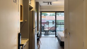 Un apartamento moderno con cocina, un balcón con una silla y un dormitorio con cama y teléfono.