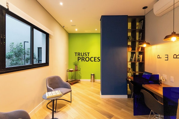 A modern office space with a green wall, a wooden desk, and a comfortable seating area. - My One Bela Vista NR (Sao Paulo)