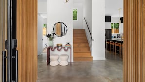 Un interior moderno con una escalera, una zona de comedor y una cocina.