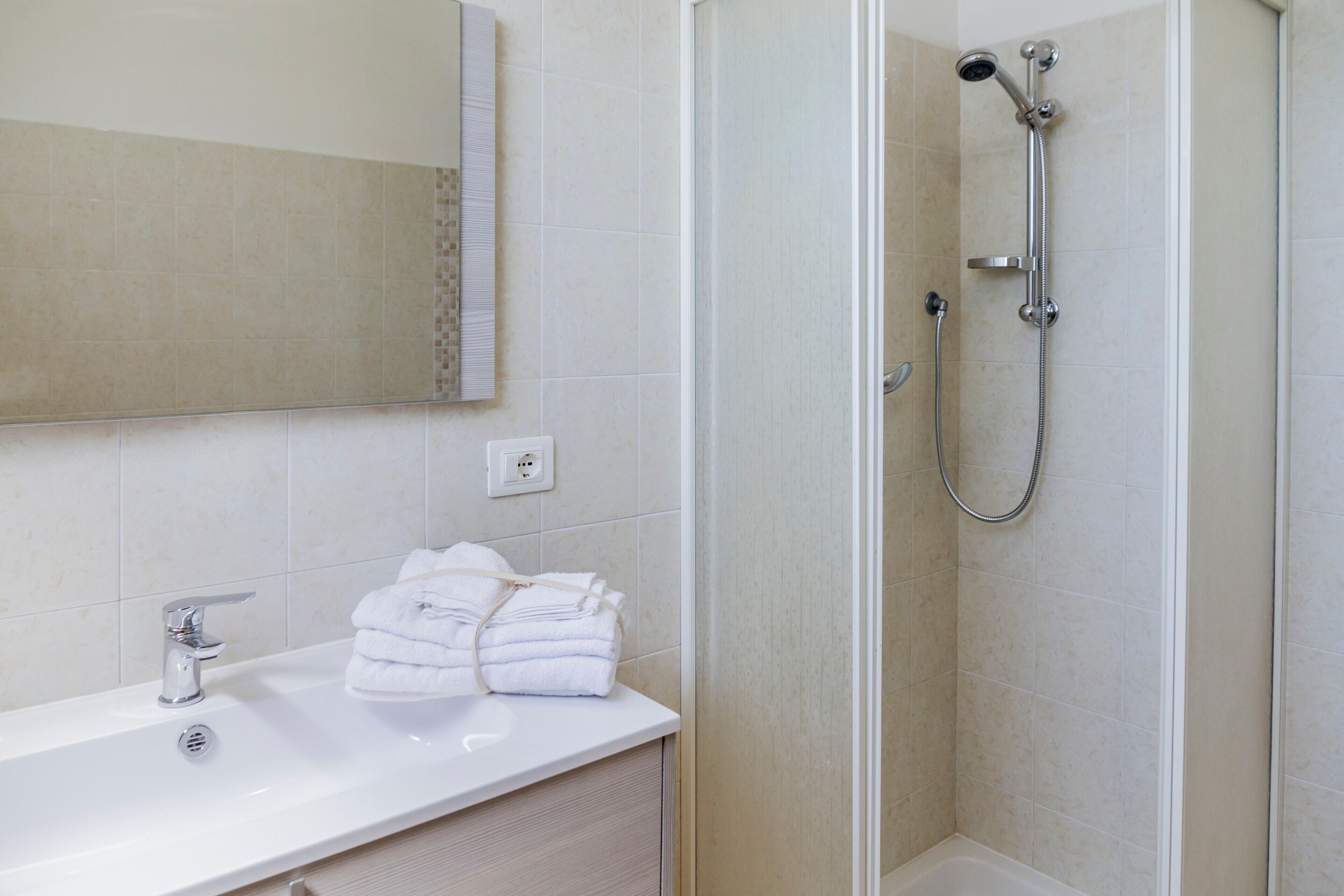A bathroom with a white sink, a mirror, and a shower.
