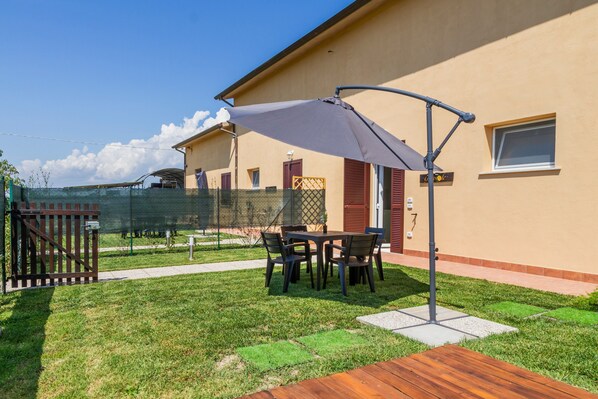 Une terrasse avec une table et des chaises, une plateforme en bois et un bâtiment à la façade beige.