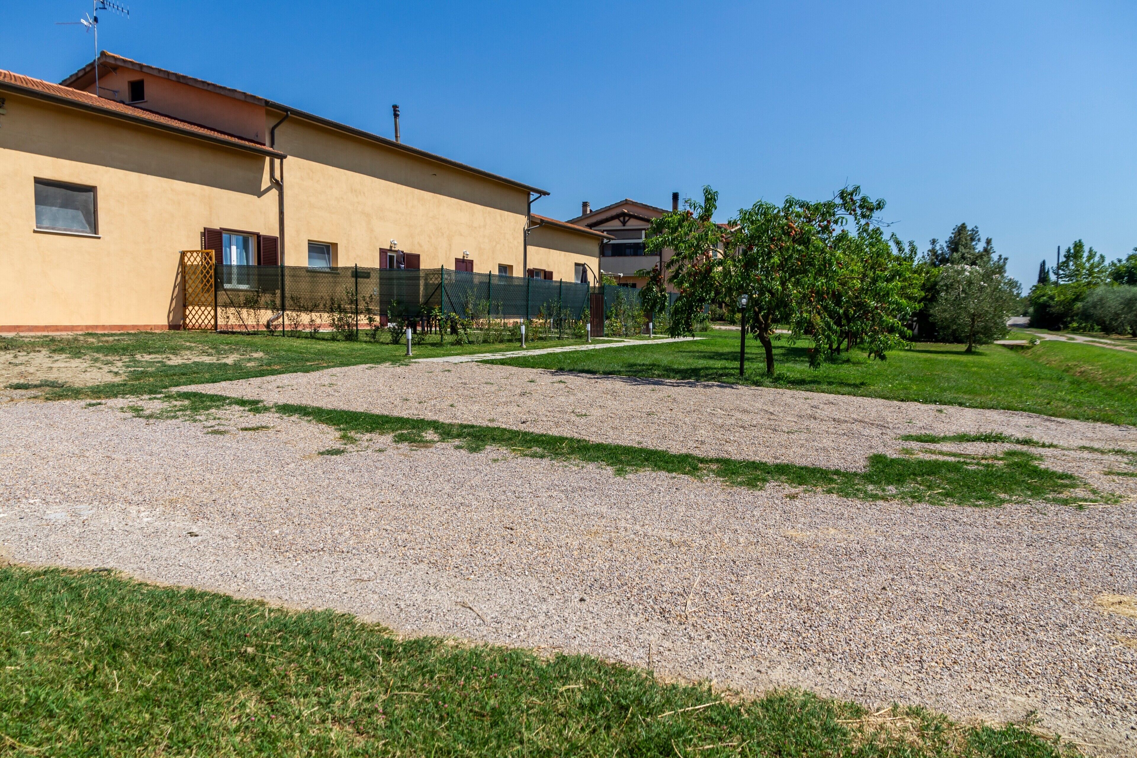 A building with a gravel driveway and a grassy area with trees.