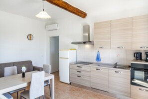 Une cuisine moderne avec des meubles de couleur bois clair, un four encastré et un coin repas comprenant une table et des chaises.