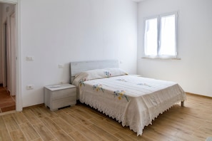 A bedroom with a bed, nightstand, and a window.
