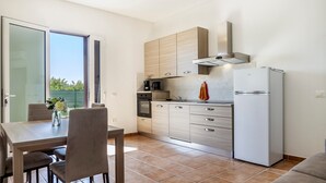 A modern kitchen with a dining area, a refrigerator, and a coffee maker.