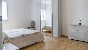 A bedroom with a bed, a chair, a dresser, and a wardrobe.