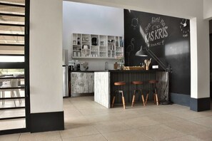 Una cocina moderna con barra, taburetes de madera y una pizarra con escritura.