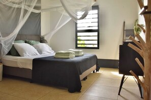 Un dormitorio con cama, mesita de noche, silla y ventana con persianas.