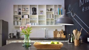 A modern kitchen with a black pendant light, a vase with flowers, and a wooden cutting board with apples.