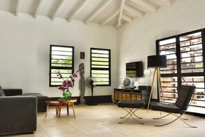 Una sala de estar con un sofá, una silla, una mesita de madera con un jarrón de flores, un globo terráqueo y una lámpara.