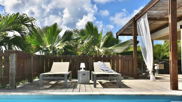 A poolside area with two lounge chairs and a wooden deck.
