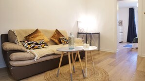 A modern living room with a brown sofa, a round coffee table, and a woven rug.
