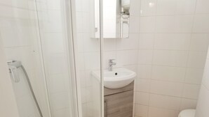 A bathroom with a glass shower enclosure, a white sink, and a toilet.