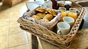 A breakfast tray with bread, juice, and a mug on a table in a room with wooden furniture and a TV. - Apart Hotel Rucaleufú (San Martín de los Andes)