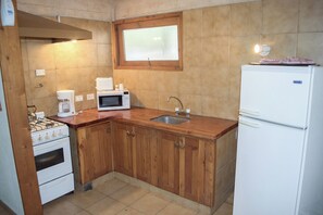 Una cocina con armarios de madera, un refrigerador blanco, un microondas, una estufa y un lavabo.