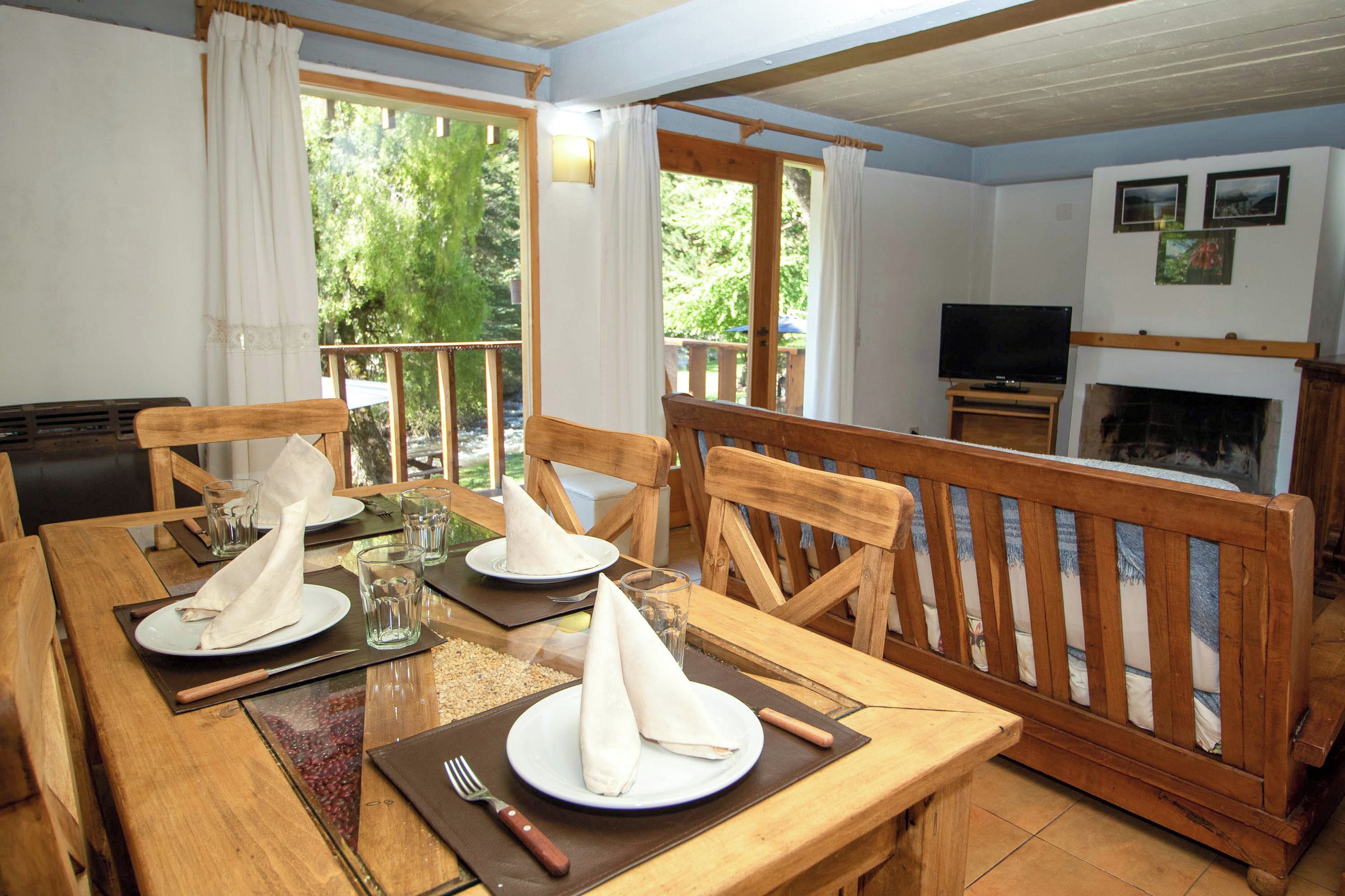 A dining area with wooden furniture, a fireplace, and a television.