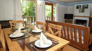 A dining area with wooden furniture, a fireplace, and a television. - Apart Hotel Rucaleufú (San Martín de los Andes)