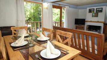A dining area with wooden furniture, a fireplace, and a television.