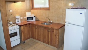 Una cocina con armarios de madera, un refrigerador blanco, un microondas, una estufa y un lavabo.