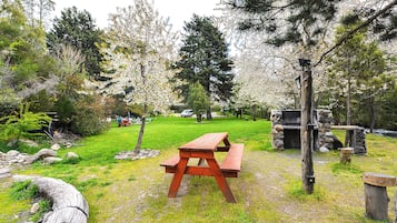 A picnic table in a park with trees and a stone bench.