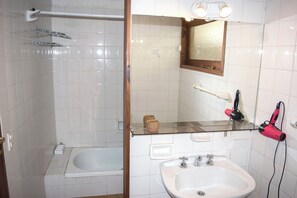 A bathroom with a glass shower enclosure, a white sink, a mirror, and a hairdryer mounted on the wall. - Apart Hotel Rucaleufú (San Martín de los Andes)